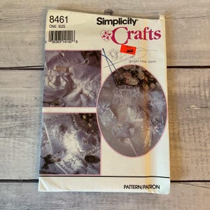 May include: A Simplicity Crafts sewing pattern envelope, number 8461, featuring white fabric accessories like pouches and decorative items. The front displays the brand name, pattern number, and images of finished white lace and fabric crafts.