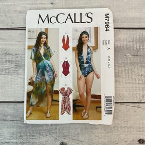 May include: McCall's sewing pattern M7964 featuring swimwear and a cover-up. The pattern includes illustrations of a halter swimsuit, a deep V-neck swimsuit, and a wrap-style cover-up. The size range is S-XL.