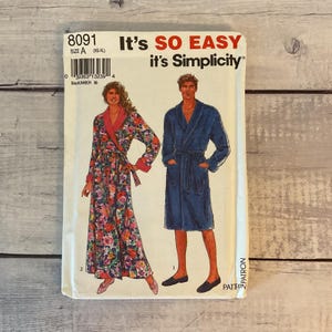 May include: A Simplicity sewing pattern envelope 8091 for robes, featuring text "It's SO EASY it's Simplicity". The illustration shows two robe styles: one long floral print robe with a solid pink collar and cuffs, and one solid blue knee-length robe.