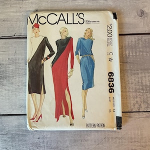 May include: A McCall's sewing pattern envelope, number 6836, for miss size 14 with a 36-inch bust. The front features illustrations of three dresses: a black and white color-blocked dress, a black and red dress, and a solid blue dress with a belt.