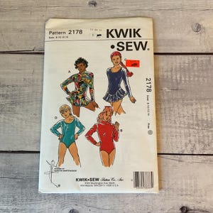 May include: A Kwik Sew pattern envelope 2178 for leotards in sizes 8-10-12-14. The front shows four illustrations of leotards labeled A, B, C, and D, featuring long sleeves, mock necks, and skirted options in red, blue, teal, and a multi-colored print.