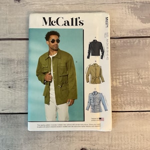 May include: McCall's sewing pattern M8371 featuring a man's jacket. The pattern includes multiple view options with simple instructions. The jacket is olive green with multiple pockets and a drawstring waist. The pattern size is AA (34-36-38-40-42).