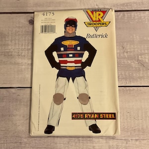 May include: A Butterick sewing pattern envelope for a VR Troopers Ryan Steel costume, model 4175. The package features a graphic of a person wearing a blue, white, and red jumpsuit with a helmet, chest armor, and knee pads, with the logo at the top.