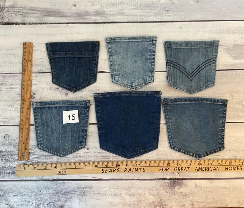 Puede incluir: Seis bolsillos de mezclilla variados en diferentes tonos de azul, desde claro hasta oscuro. Un bolsillo tiene una etiqueta blanca con el n&uacute;mero 15. Una regla de madera est&aacute; colocada vertical y horizontalmente para mostrar la escala en cent&iacute;metros.