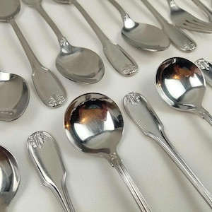 Peut inclure: Un assortiment de cuillères de service, de fourchettes et d'ustensiles de service en argent poli. L'argenterie présente des accents floraux décoratifs sur les manches. Les cuillères ont différentes formes de cuillères, rondes et ovales. Les ustensiles sont disposés sur une surface blanche.