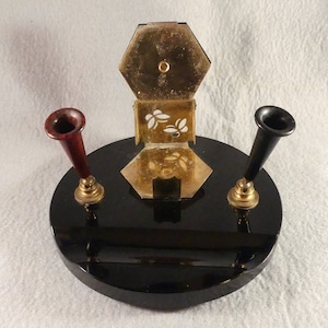 May include: A black desk organiser with a gold metal pen holder and two pen holders, one red and one black.