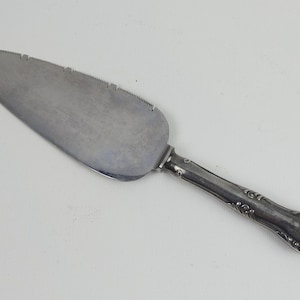 May include: A silver cake server with a serrated edge and an ornate handle.