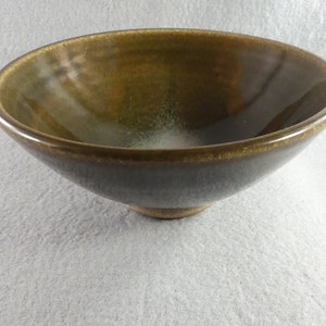 May include: A dark green ceramic bowl with a white glaze on the inside. The bowl has a rounded shape and a slightly flared rim.