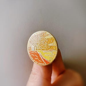 May include: A gold-toned enamel pin featuring a stylized illustration of a TARDIS with a sunset and starry sky background. The text "THE POWER OF THE DOCTOR" is written around the bottom of the pin.