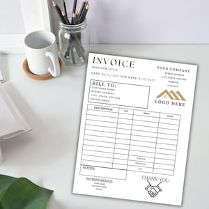 May include: A white invoice with the word "INVOICE" at the top. The invoice includes fields for customer information, a description of services, and payment details. A logo of three houses is present. A white mug and pencils are in the background.