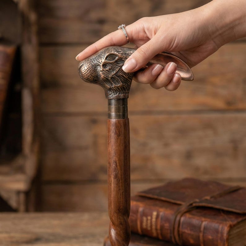 Puede incluir: Bast&oacute;n decorativo con un mango de cabeza de conejo de bronce y un eje de madera oscura. El mango est&aacute; detallado con los rasgos del conejo, y el eje tiene un dise&ntilde;o retorcido. El bast&oacute;n es un accesorio elegante.