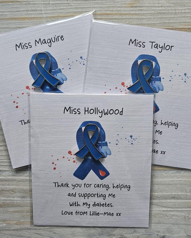 May include: Three blue awareness ribbon pins attached to white cards. Each card features a name at the top and text below the pin. The pin displays a blue ribbon with a small red droplet icon. The cards include printed messages of gratitude.