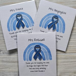 May include: Three blue enamel heart-shaped awareness ribbon pins attached to white cards. Each card features a watercolor-style blue rainbow illustration and printed text including names like Mrs France, Mrs Nagington, and Mrs Rothwell.