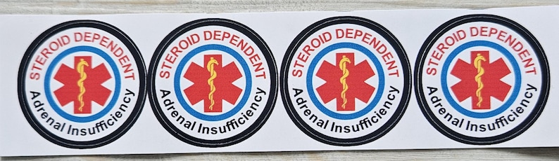 Pu&ograve; includere: Quattro adesivi rotondi con la scritta "Steroid Dependent Adrenal Insufficiency". Presentano una stella rossa con un simbolo medico giallo, circondata da bordi blu e neri, su sfondo bianco.
