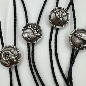 以下が含まれることがあります： 黒い編み込みコードが付いた、4つの銀色のボーラタイ。各ボーラタイは、詳細なレリーフデザインの円形ペンダントを備えています。羊、鹿、鳥、魚です。ペンダントは素朴でアンティークな外観をしています。