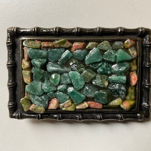 May include: A green and pink stone mosaic belt buckle with a dark brown metal frame. The frame has a bamboo-like design.