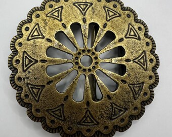 May include: A round, antique gold-colored belt buckle with a scalloped edge. The buckle features a central opening with radiating spokes and is decorated with triangular and dot patterns.