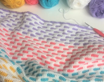 May include: A colourful crocheted blanket with stripes of purple, pink, turquoise, and yellow yarn. The blanket is made with a simple stitch pattern and has a soft, textured feel.