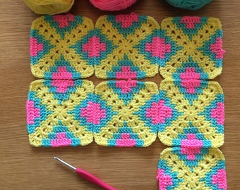 May include: A set of crocheted squares in yellow, pink, and blue. The squares are arranged in a pattern and are ready to be sewn together to create a larger project.