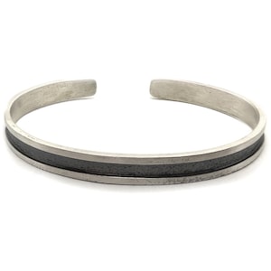 May include: A silver bangle bracelet with a black band around the center.