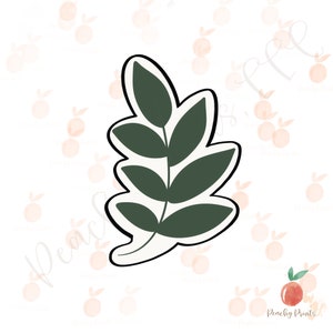 May include: A green leaf cookie cutter with a simple design. The cutter is made of metal and has a smooth, rounded edge.