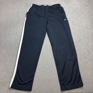 May include: Navy blue athletic pants with a white stripe down the left leg. The pants have a drawstring waist and a small white Nike logo on the upper left leg. The pants are made of a lightweight material.