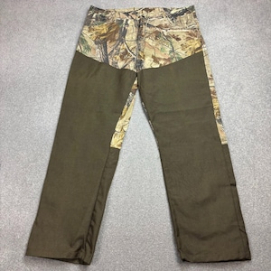 Puede incluir: Pantalones de camuflaje con paneles de color verde oliva liso en la parte delantera de las piernas. El diseño de camuflaje presenta tonos de marrón, beige y verde. Los pantalones tienen cierre de botón y cremallera.