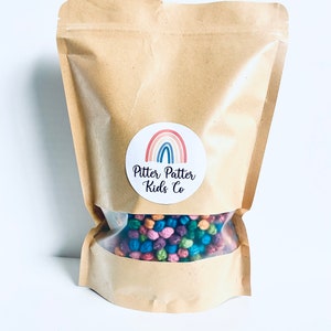 May include: A brown paper bag with a sticker that says "Pitter Patter Kids Co." and a rainbow design. The bag contains a variety of colorful sensory balls.