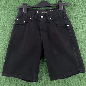 May include: Black denim shorts with a button fastening and pockets. The shorts are hanging on a black hanger. The word "loose" is visible on the waistband.