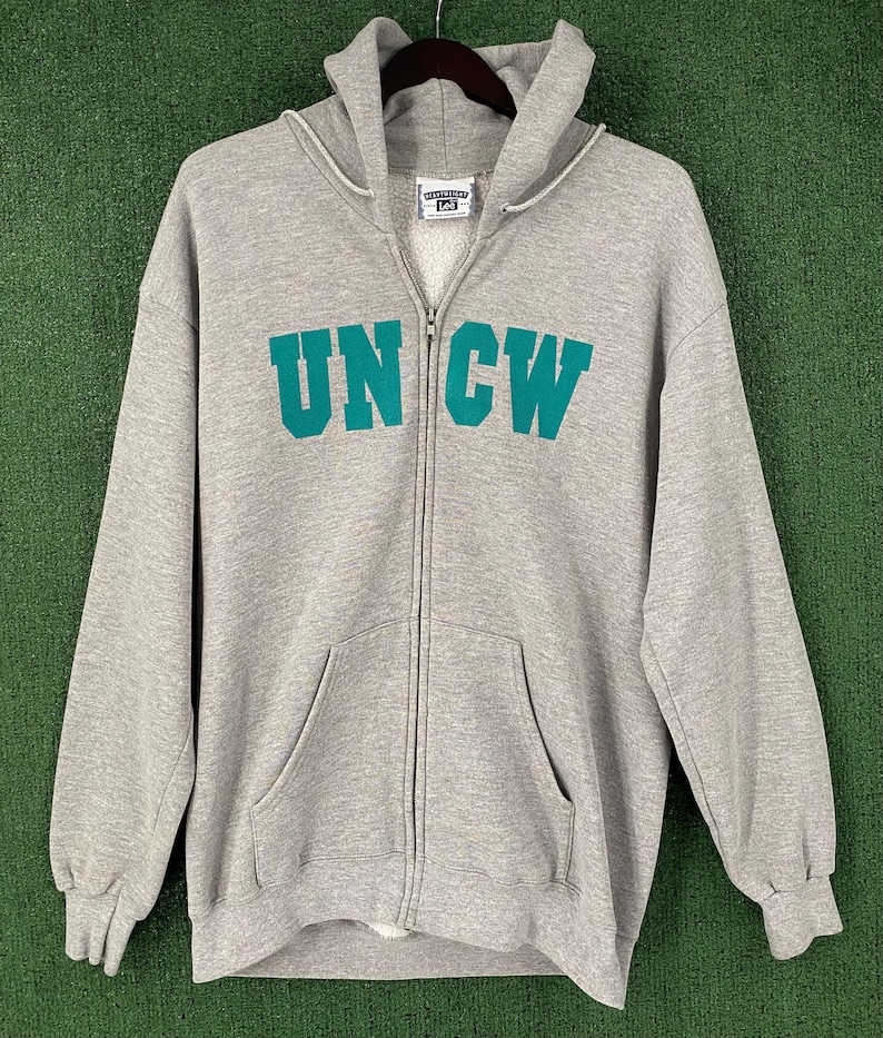 May include: A grey zip-up hoodie featuring the teal letters "UNCW". The hoodie has a hood, a full-length zip, and a kangaroo pocket. The brand label "Lee" is visible at the top.
