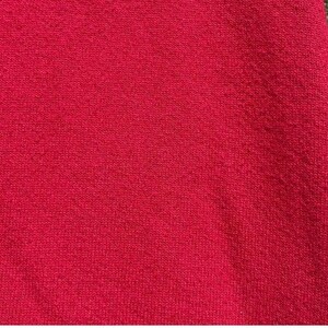 Może przedstawiać: Zbliżenie na żywy czerwony materiał z teksturowanym wzorem dzianiny. Materiał jest w jednolitym kolorze, bez widocznych wzor&oacute;w i deseni. Tkanina jest prawdopodobnie tekstylna, być może do odzieży lub wystroju domu.