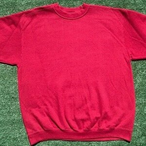 Może przedstawiać: Gładka czerwona bluza z okrągłym dekoltem i długimi rękawami. Odzież wykonana jest z miękkiego materiału i leży płasko na zielonej powierzchni. Rękawy są rozłożone na boki.