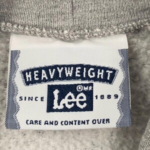May include: Close-up of a grey sweatshirt collar with a white label. The label displays the text "HEAVYWEIGHT" and the Lee logo in navy blue. The label also includes the text "SINCE 1889" and "CARE AND CONTENT OVER".