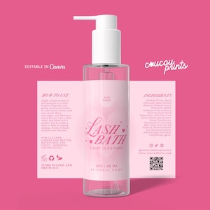 May include: A clear plastic pump bottle of lash bath cleanser with a pink label featuring heart graphics and text including Lash Bath, ingredients, and instructions. Behind the bottle is a matching pink rectangular label template with text.