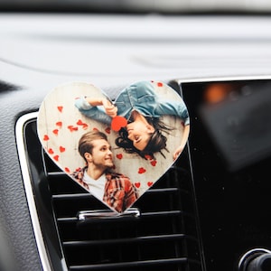 May include: A heart-shaped car air freshener with a photo of a couple looking at each other. The photo is surrounded by small red hearts.