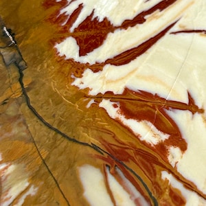 Puede incluir: Primer plano de una piedra pulida con un patrón de remolino de blanco, marrón y rojo.