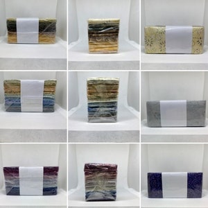 May include: Nine stacks of fabric squares, each stack wrapped in clear plastic and tied with a white ribbon. The fabric squares are in various patterns and colors, including floral, geometric, and abstract.