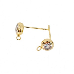 May include: Gold-tone earring findings with a clear crystal stone. The findings have a loop on the bottom and a post on the top.