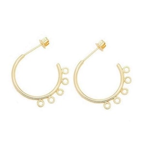 May include: A pair of gold-colored hoop earrings. Each earring has a post for insertion and a curved design with multiple small loops for attaching charms or other decorative elements. The earrings are set against a white background.