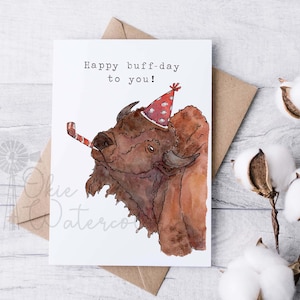 May include: A greeting card with a watercolor illustration of a brown buffalo wearing a red and white party hat and blowing a red and white party horn. The text on the card reads "Happy buff-day to you!"