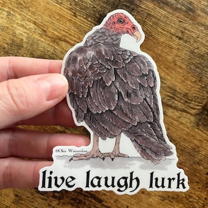 May include: A sticker featuring a cartoon illustration of a turkey vulture with a red head and the text "live laugh lurk".