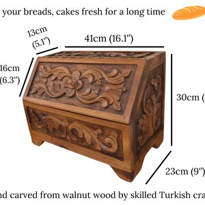 May include: A brown wooden bread box with intricate floral carvings on the front and side panels. The box measures 41 cm long, 13 cm deep, 16 cm high, and 23 cm wide. Text reads: Keep your breads, cakes fresh for a long time.
