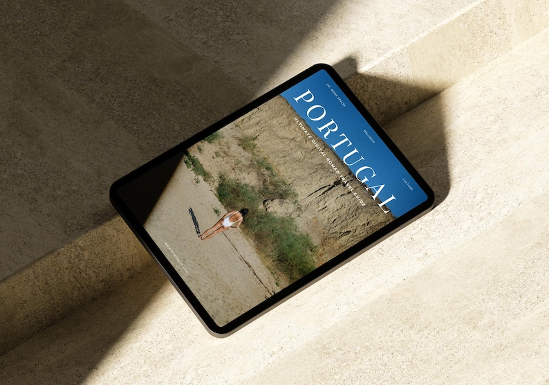 May include: A tablet computer displaying a magazine cover with the word "PORTUGAL" in large blue letters. The cover features a photo of a person in a white swimsuit standing on a sandy beach.