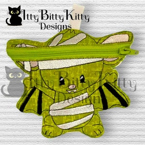 May include: A green and white mummy bat zipper pouch with a green zipper. The pouch has a stitched-on face with black eyes and a stitched-on mouth. The text "Itty Bitty Kitty Designs" is stitched on the top of the pouch.