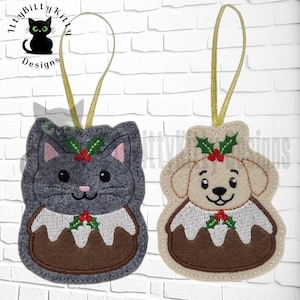 May include: Two felt Christmas ornaments: a gray cat and a beige dog, each with a Christmas pudding design. The cat has pink ears and the dog has a black nose. Both have holly accents and gold ribbon hangers.