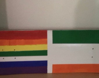 May include: A skateboard deck painted with the colors of the rainbow flag on one side and the Irish flag on the other side.