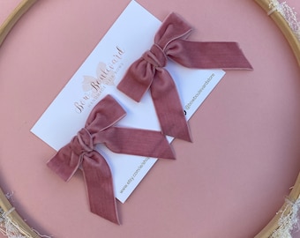 May include: Two dusty rose velvet hair bows on a white card with the text "Bow Boulevard Handmade Hair Bows" and the website address "www.etsy.com/ie/shop/bowboulevardstore".