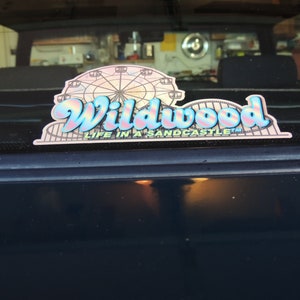 May include: A blue and pink sticker with the text "Wildwood Life in a Sandcastle" and a graphic of a Ferris wheel.
