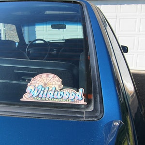 May include: A blue car with a sticker on the rear window that reads "Wildwood Life in a Sandcastle" and features a Ferris wheel graphic.