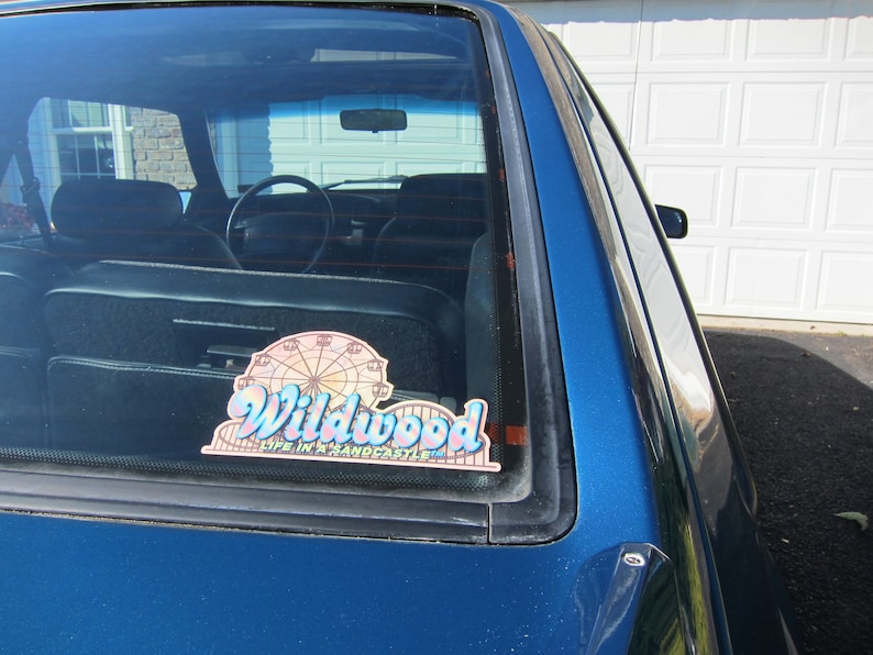 May include: A blue car with a sticker on the rear window that reads "Wildwood Life in a Sandcastle" and features a Ferris wheel graphic.